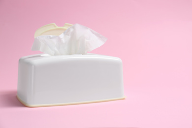 Photo of Holder with paper tissues on pink background