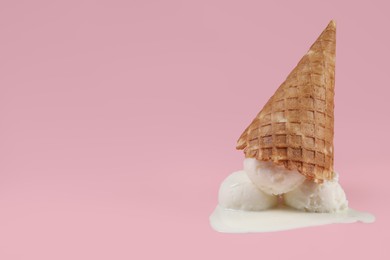 Photo of Melting ice cream and wafer cone on pink background, space for text