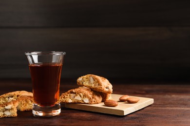 Photo of Tasty cantucci and glass of liqueur on wooden table, space for text. Traditional Italian almond biscuits