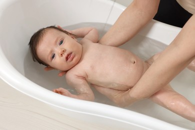 Photo of Mother bathing her little baby in bathtub, closeup