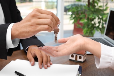 Photo of Real estate agent giving keys to woman at table
