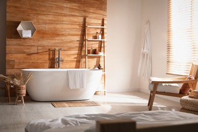 Photo of Stylish apartment interior with white bathtub and bed