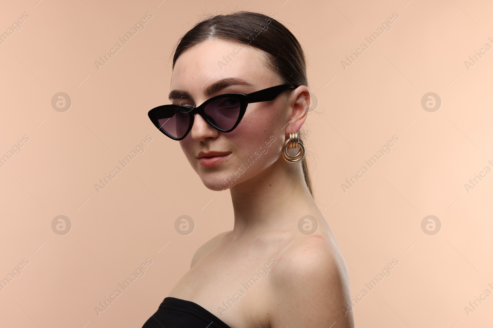 Portrait of beautiful young woman with sunglasses on beige background Photo of Portrait of beautiful young woman with sunglasses on beige background