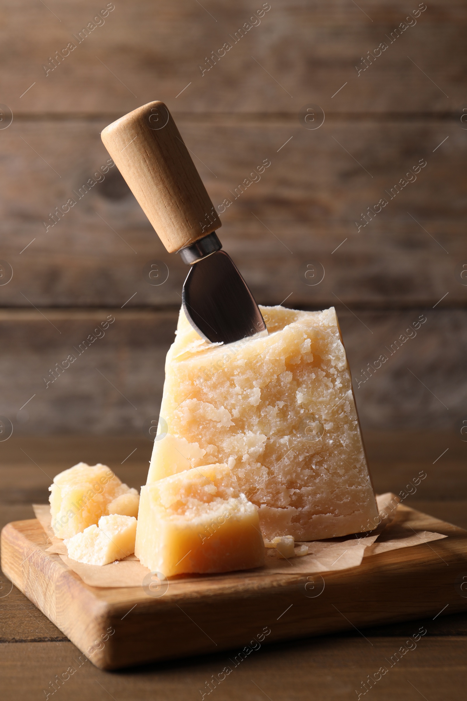 Photo of Delicious parmesan cheese with knife on wooden table