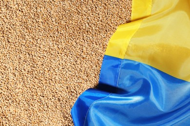 Photo of National flag of Ukraine on wheat grains, top view. Global food crisis concept
