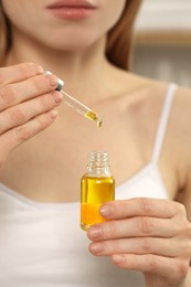 Photo of Woman with bottle of essential oil on blurred background, closeup