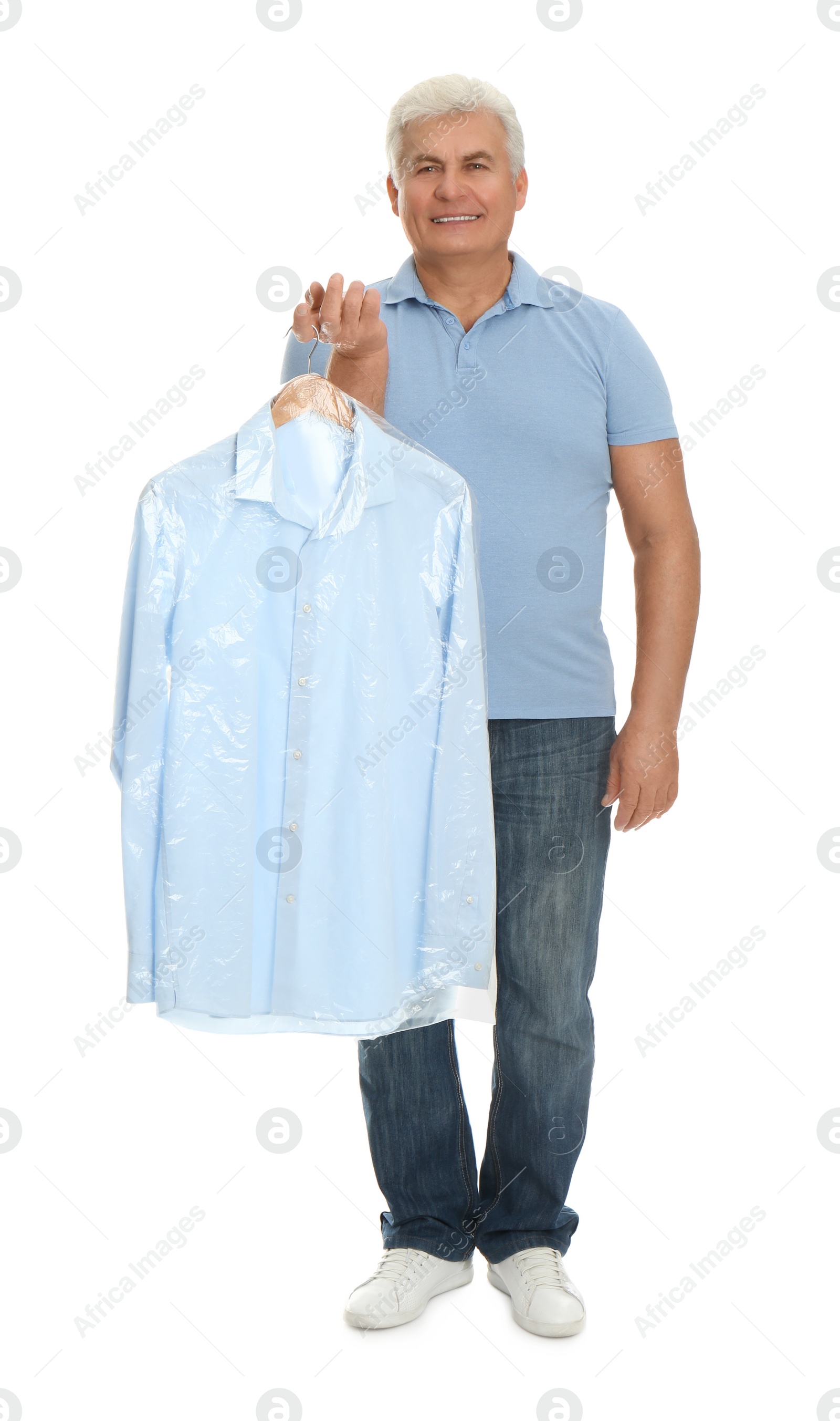 Photo of Senior man holding hanger with shirt in plastic bag on white background. Dry-cleaning service