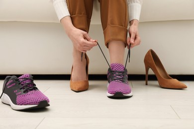 Photo of Woman changing shoes on sofa in office, closeup