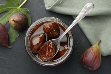 Photo of Jar of tasty sweet jam and fresh figs on black table, flat lay
