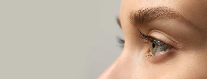 Image of Closeup view of woman with beautiful eyes on light grey background, space for text. Banner design