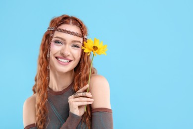 Photo of Beautiful young hippie woman with sunflower on light blue background, space for text