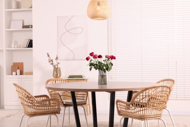 Photo of Chairs and table with vase of red rose flowers in dining room. Stylish interior