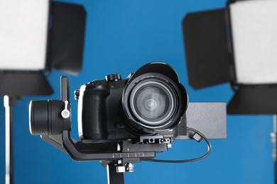 Photo of Professional video camera and lighting equipment on blue background
