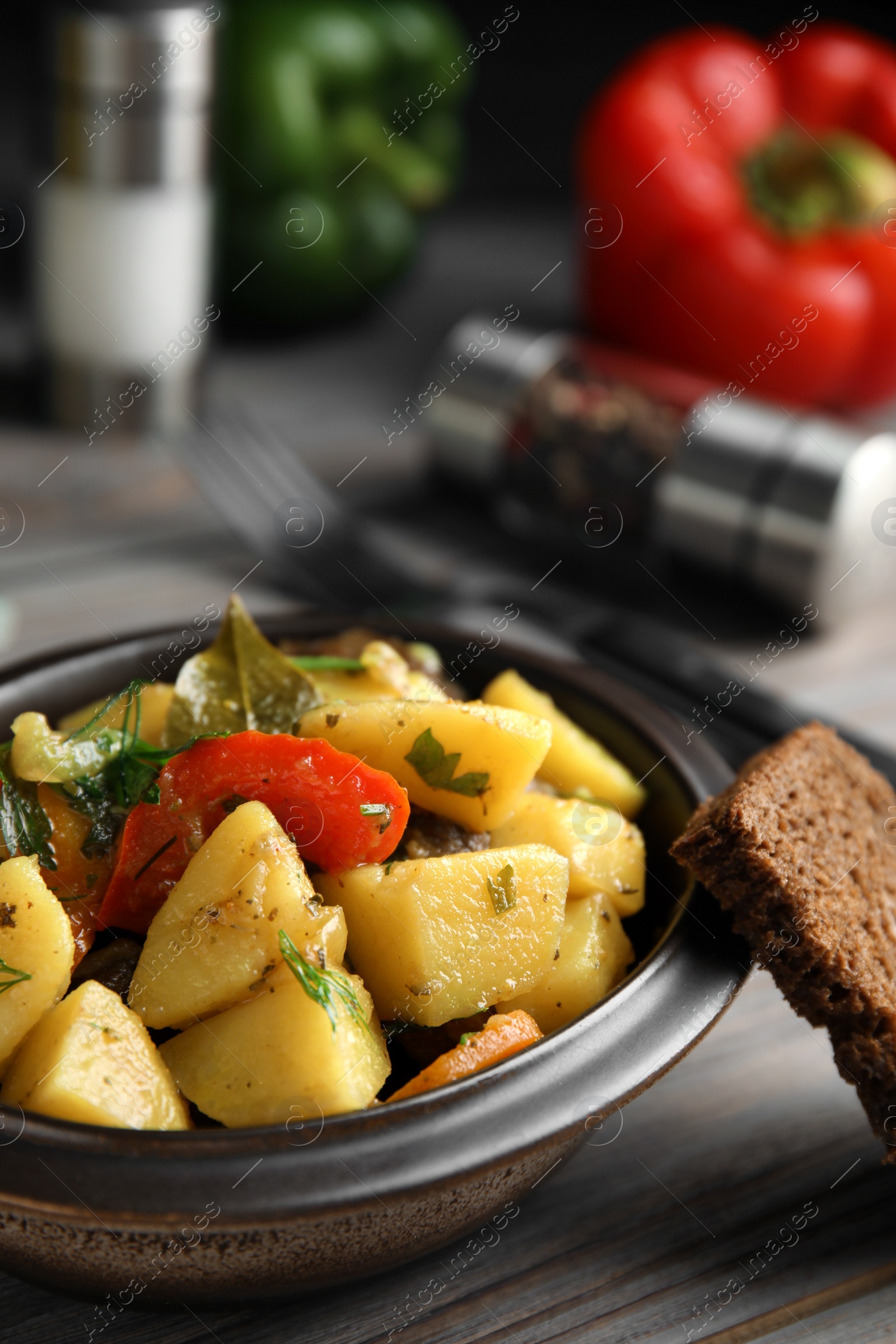 Photo of Tasty cooked dish with potatoes in earthenware on wooden table