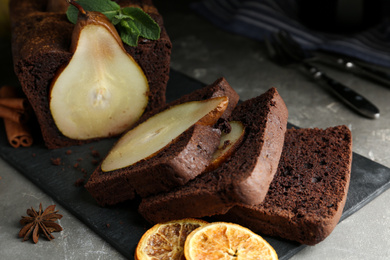 Photo of Tasty pear bread with spices, dried orange slices and mint on grey table. Homemade cake