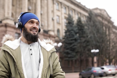 Photo of Mature man with headphones listening to music outdoors