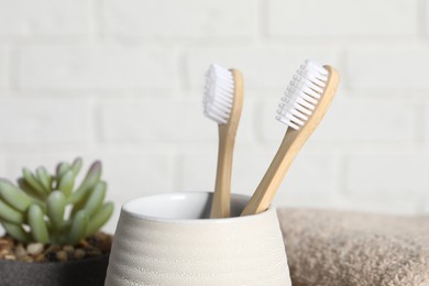 Photo of Bamboo toothbrushes in holder on blurred background, closeup