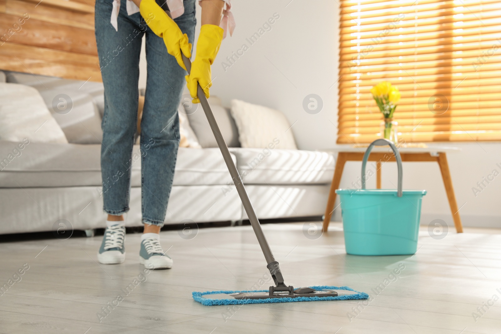 Photo of Woman cleaning floor with mop at home, closeup