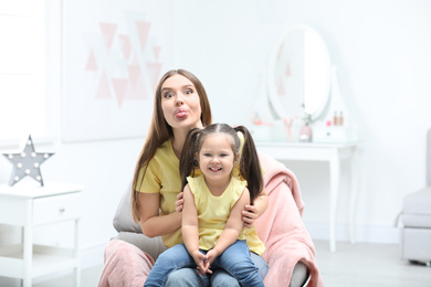 Photo of Young mother with little daughter having fun at home