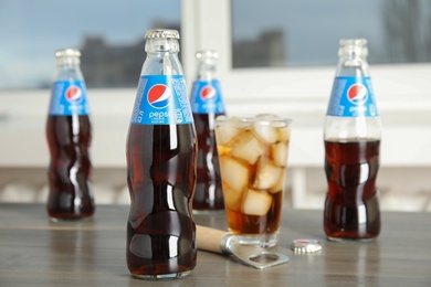 Photo of MYKOLAIV, UKRAINE - FEBRUARY 10, 2021: Bottles and glass of Pepsi on wooden table