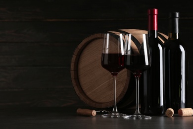 Photo of Composition with glasses and bottles of red wine on table against dark background. Space for text