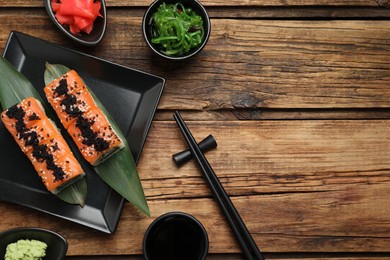 Photo of Delicious sushi rolls served on wooden table, flat lay. Space for text