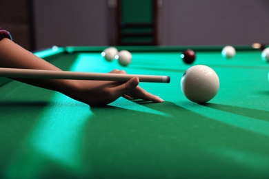 Photo of Young woman playing Russian billiard indoors, closeup