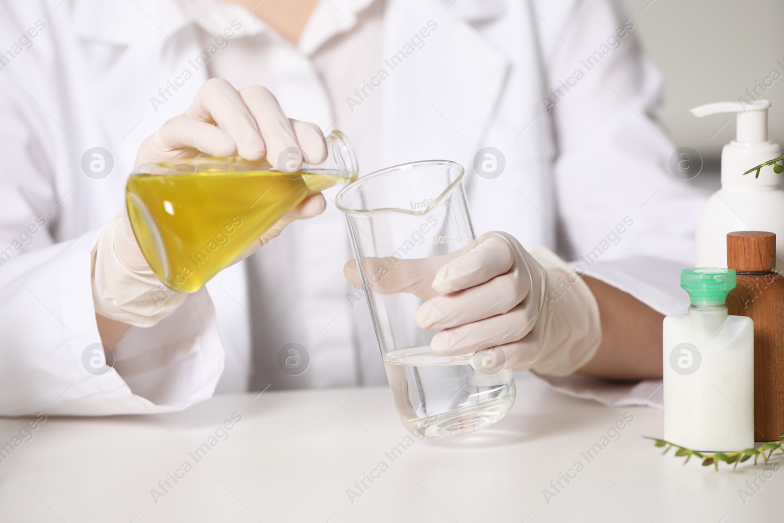 Photo of Dermatologist developing cosmetic product at white table indoors, selective focus