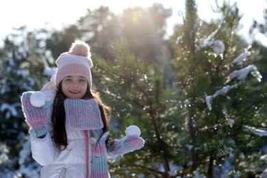 Photo of Cute little girl with snowballs in winter forest