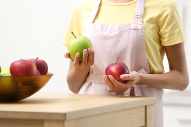 Photo of Woman holding fresh apples in kitchen, closeup