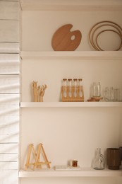 Wooden shelves with decorative elements and supplies in studio. Artist's workplace