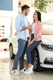 Photo of Happy couple with car key in modern auto dealership