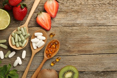 Different vitamin pills and fresh fruits on old wooden table, flat lay. Space for text