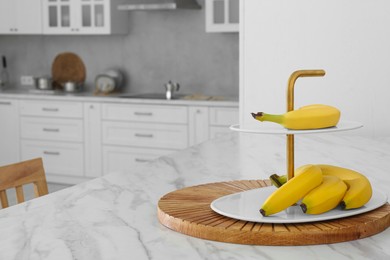 Fruit stand with bananas on white marble table in kitchen. Interior design\