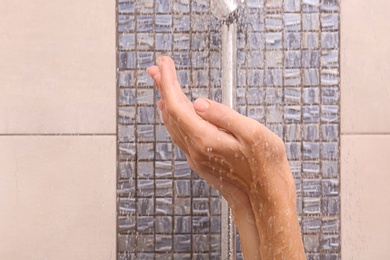 Photo of Young woman taking shower, focus on hands