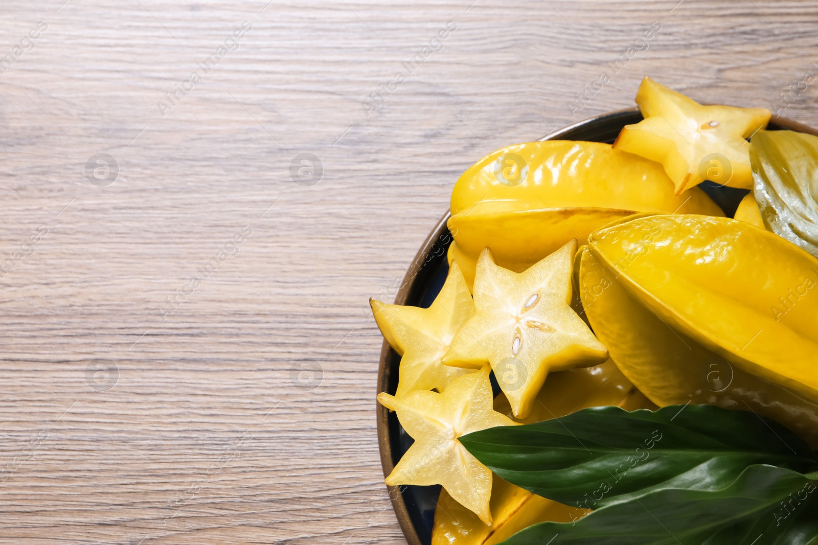Photo of Delicious carambola fruits on wooden table, top view. Space for text
