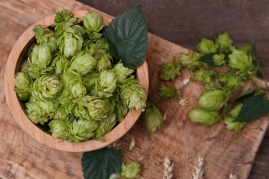 Fresh green hops and ears of wheat on wooden table, flat lay