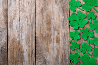 Photo of Flat lay composition with clover leaves on wooden table, space for text. St. Patrick's Day celebration