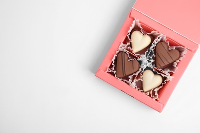 Photo of Tasty heart shaped chocolate candies on white background, top view. Happy Valentine's day