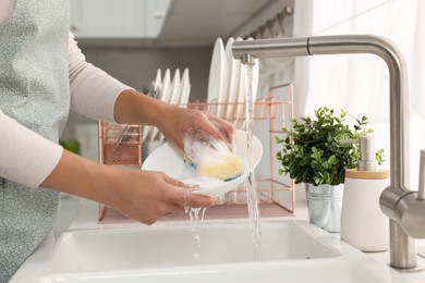 Photo of Woman washing bowl at sink in kitchen, closeup