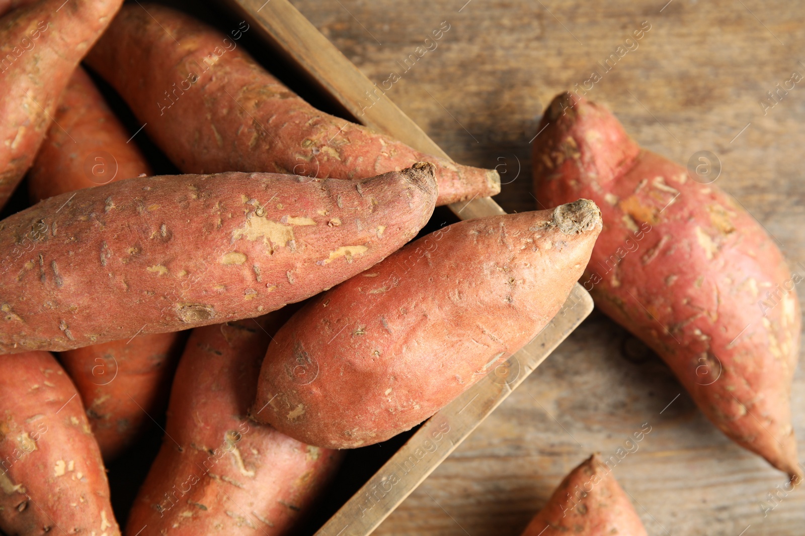 Photo of Wooden crate with sweet potatoes on table, top view