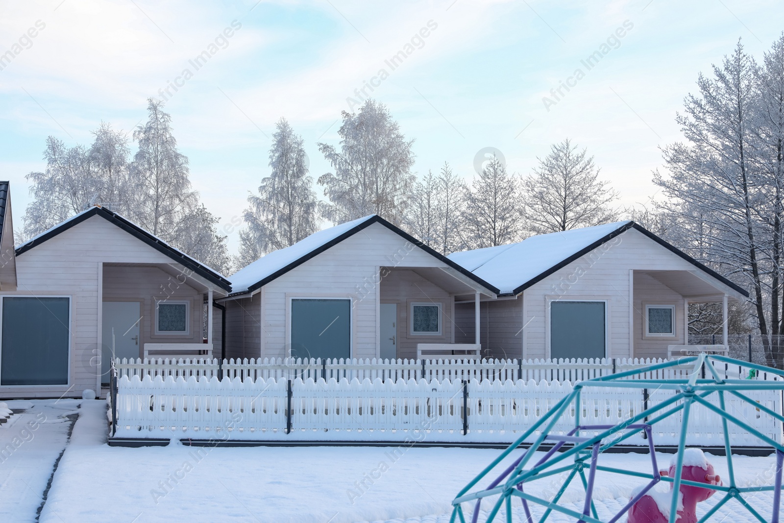 Photo of Wooden houses and trees covered with snow in winter morning