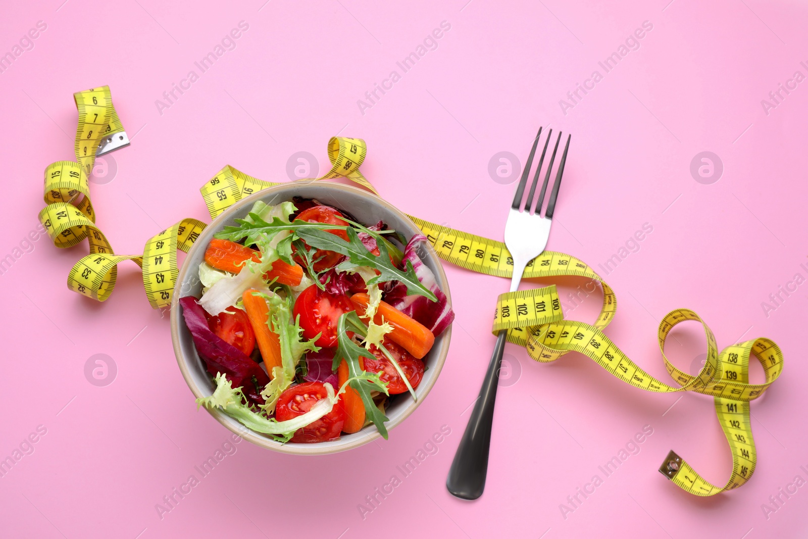Photo of Healthy salad with measuring tape on pink background, flat lay. Diet concept