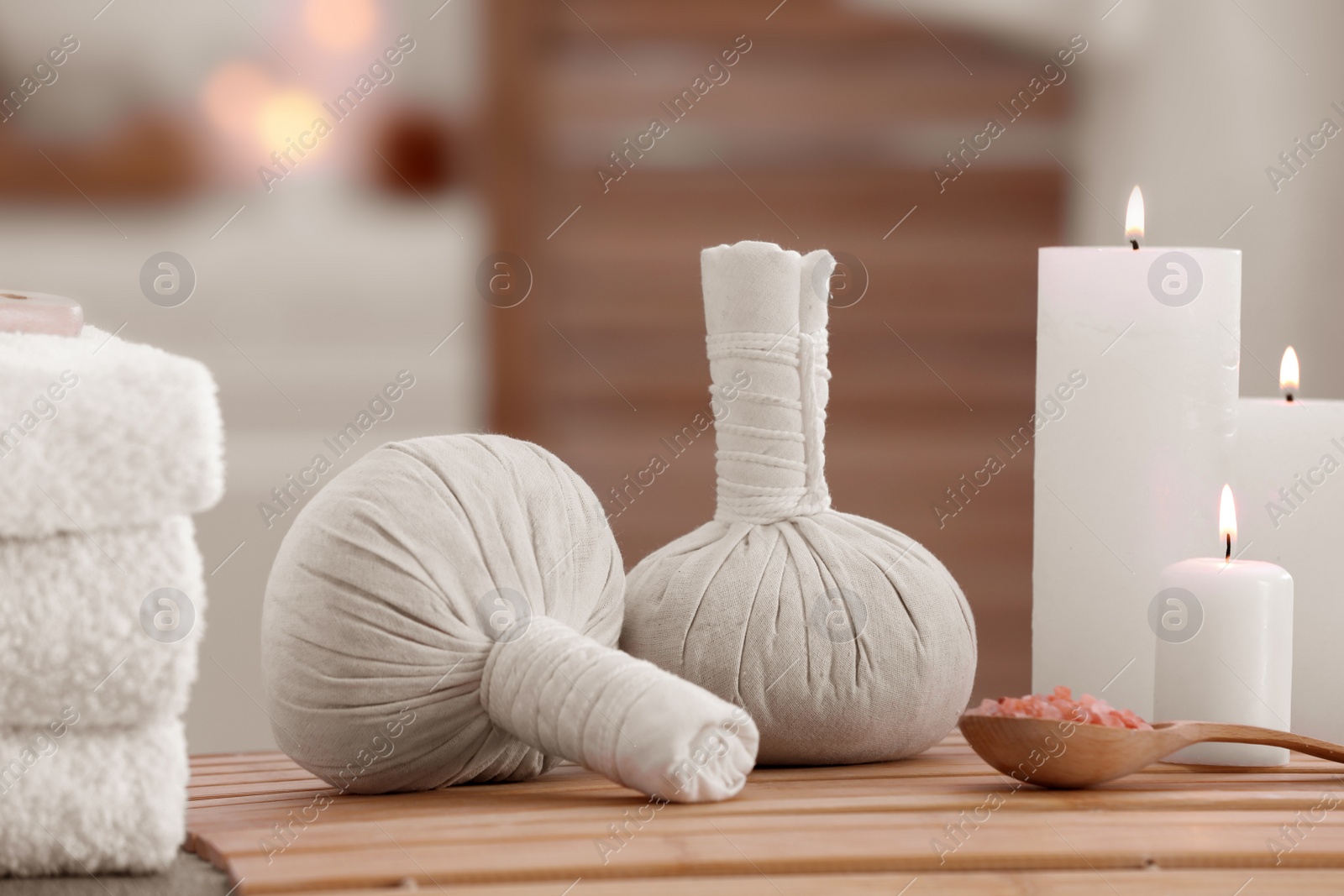 Photo of Spa composition with burning candles and herbal bags on massage table in wellness center