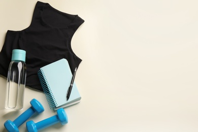Photo of Flat lay composition with sportswear and notebook on light background, space for text. Gym workout plan