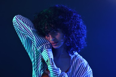 Photo of Beautiful young woman posing on color background in neon lights