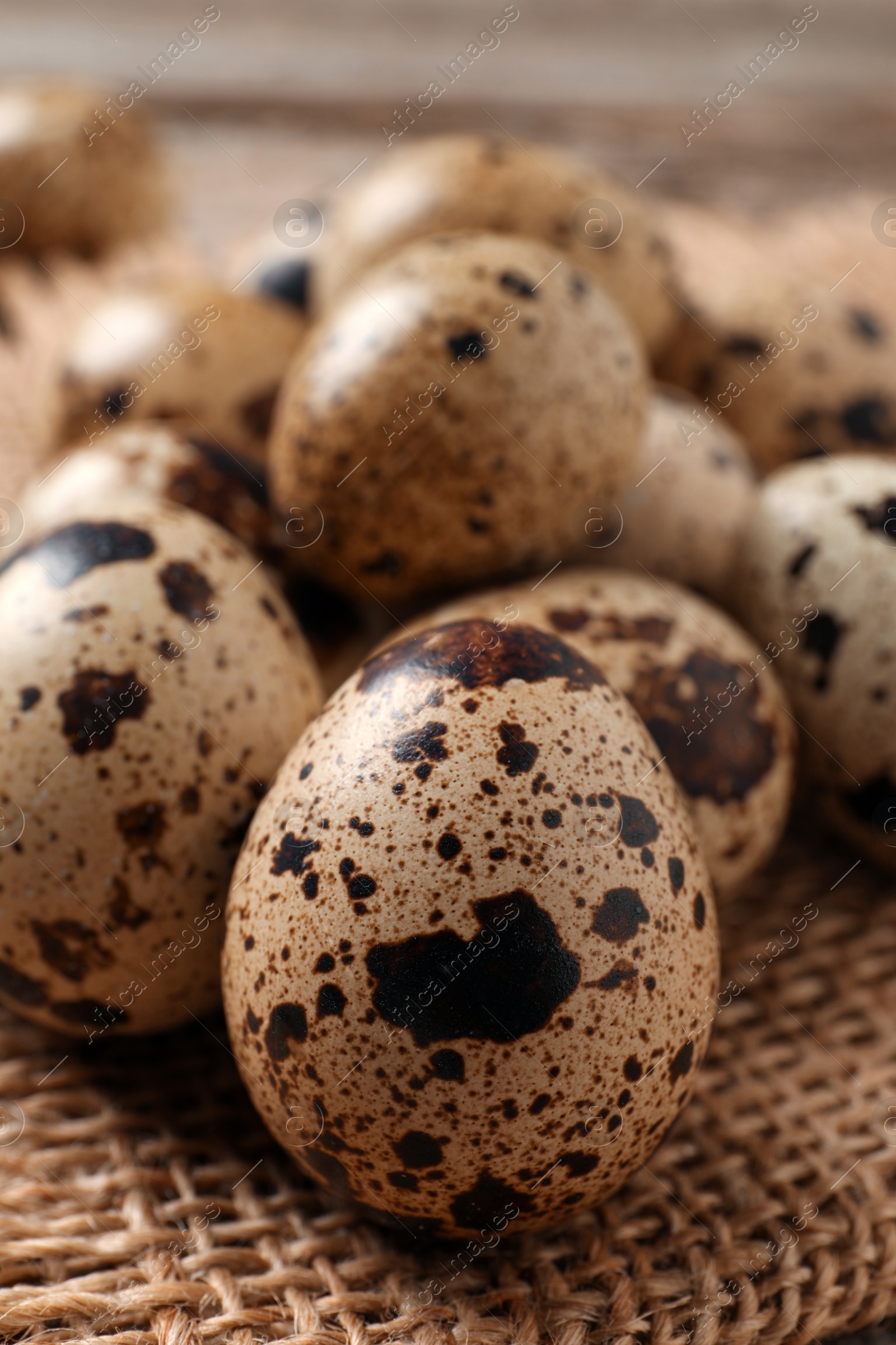 Photo of Fresh quail eggs on burlap fabric, closeup