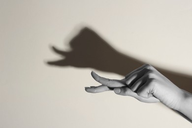 Shadow puppet. Woman making hand gesture like snail on light background, closeup with space for text. Black and white effect