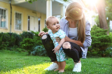 Photo of Teen nanny with cute baby on green grass outdoors