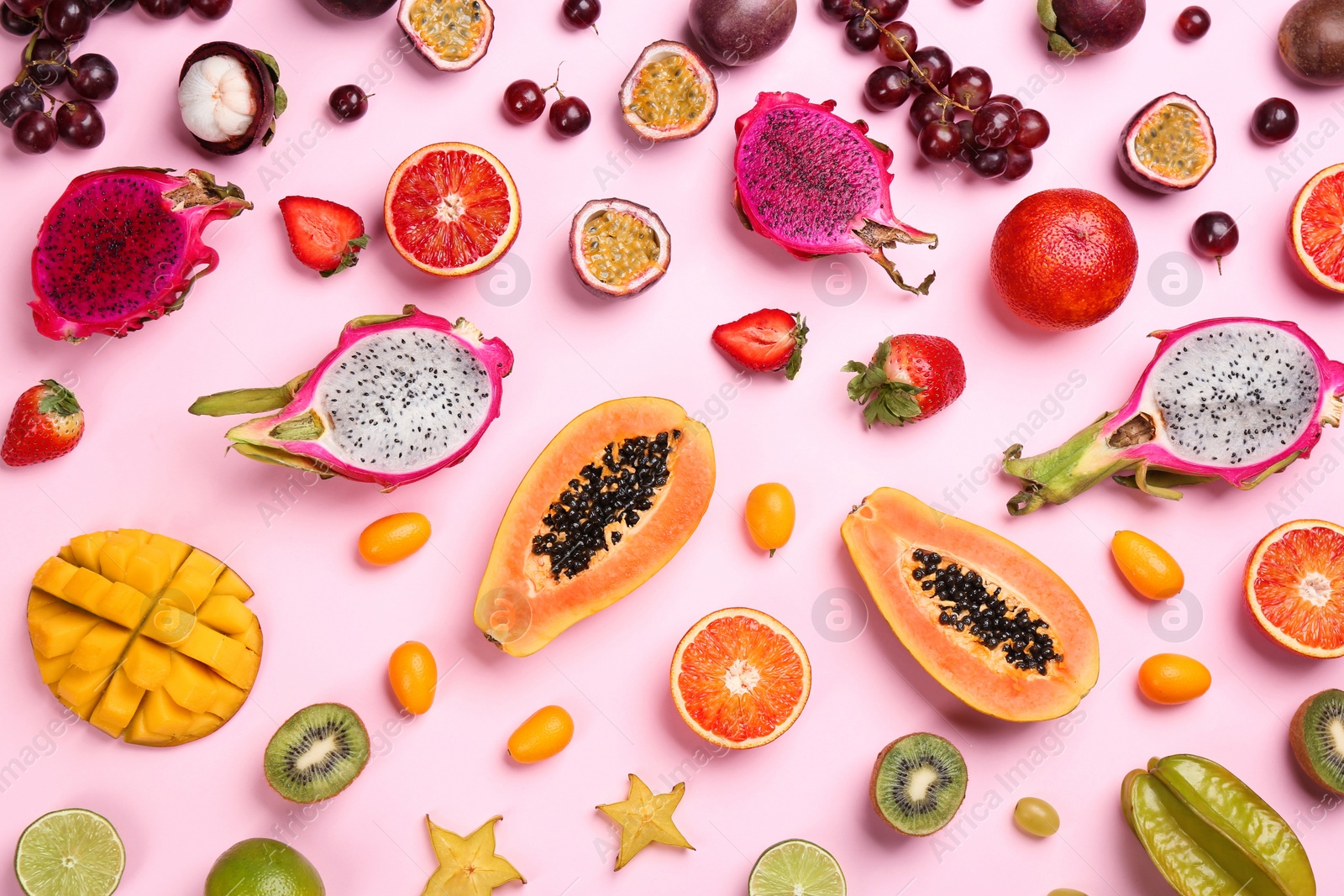 Photo of Many different delicious exotic fruits on pink background, flat lay